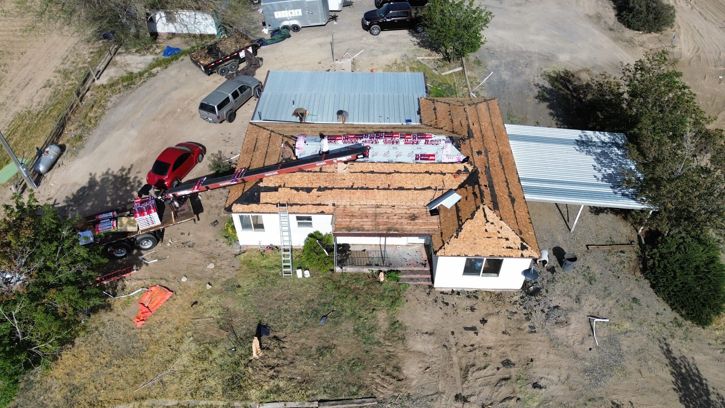 Aerial view of a re-roofing project with crew loading shingles onto the roof