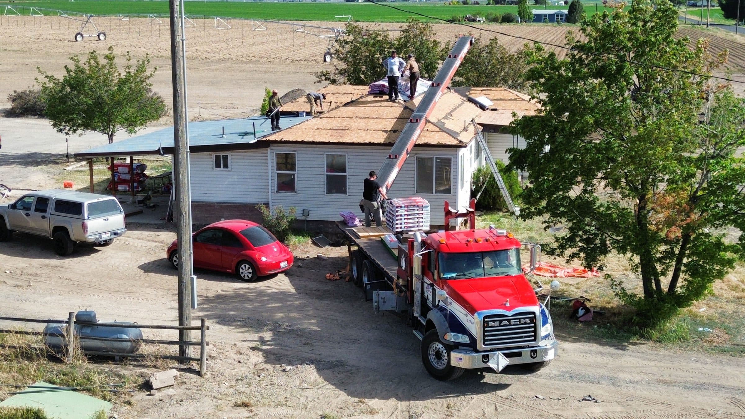Roofing crew installing a new roof with materials delivered by boom truck
